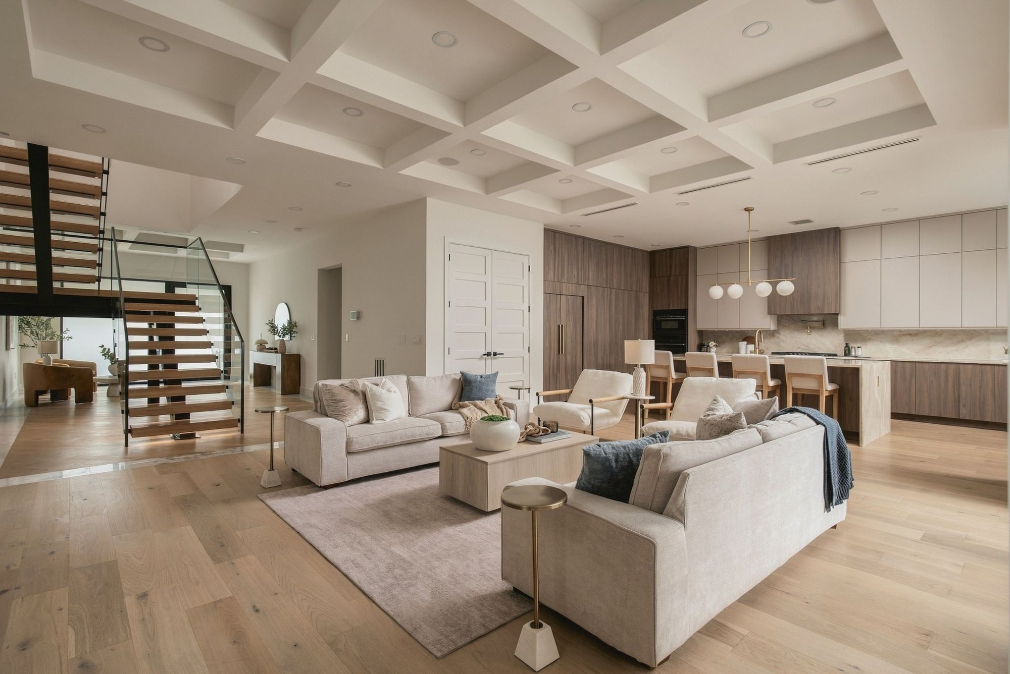 Open living room with a coffered ceiling and a floating staircase