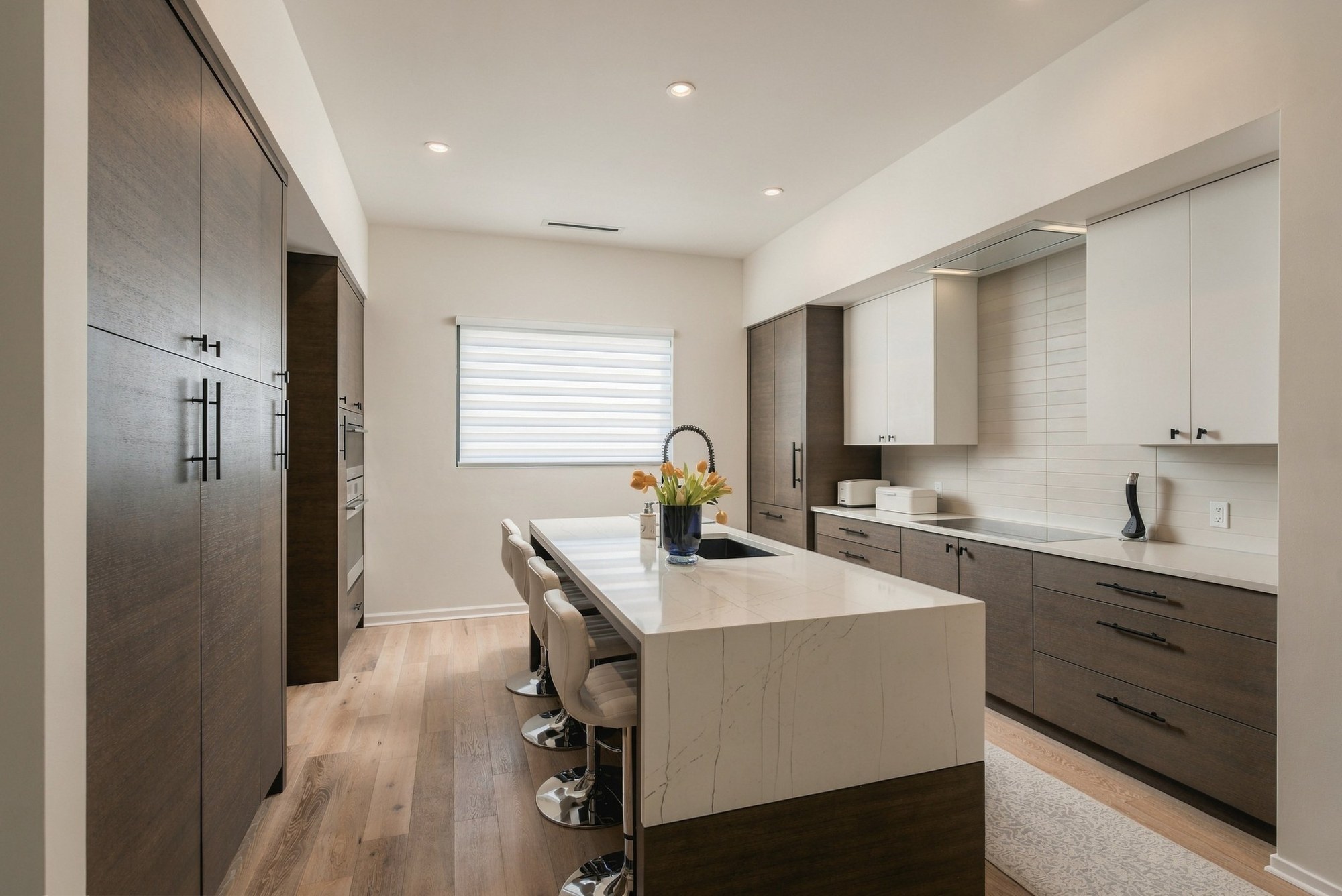 Modern kitchen with a waterfall island, dark wood cabinets and white upper cabinets